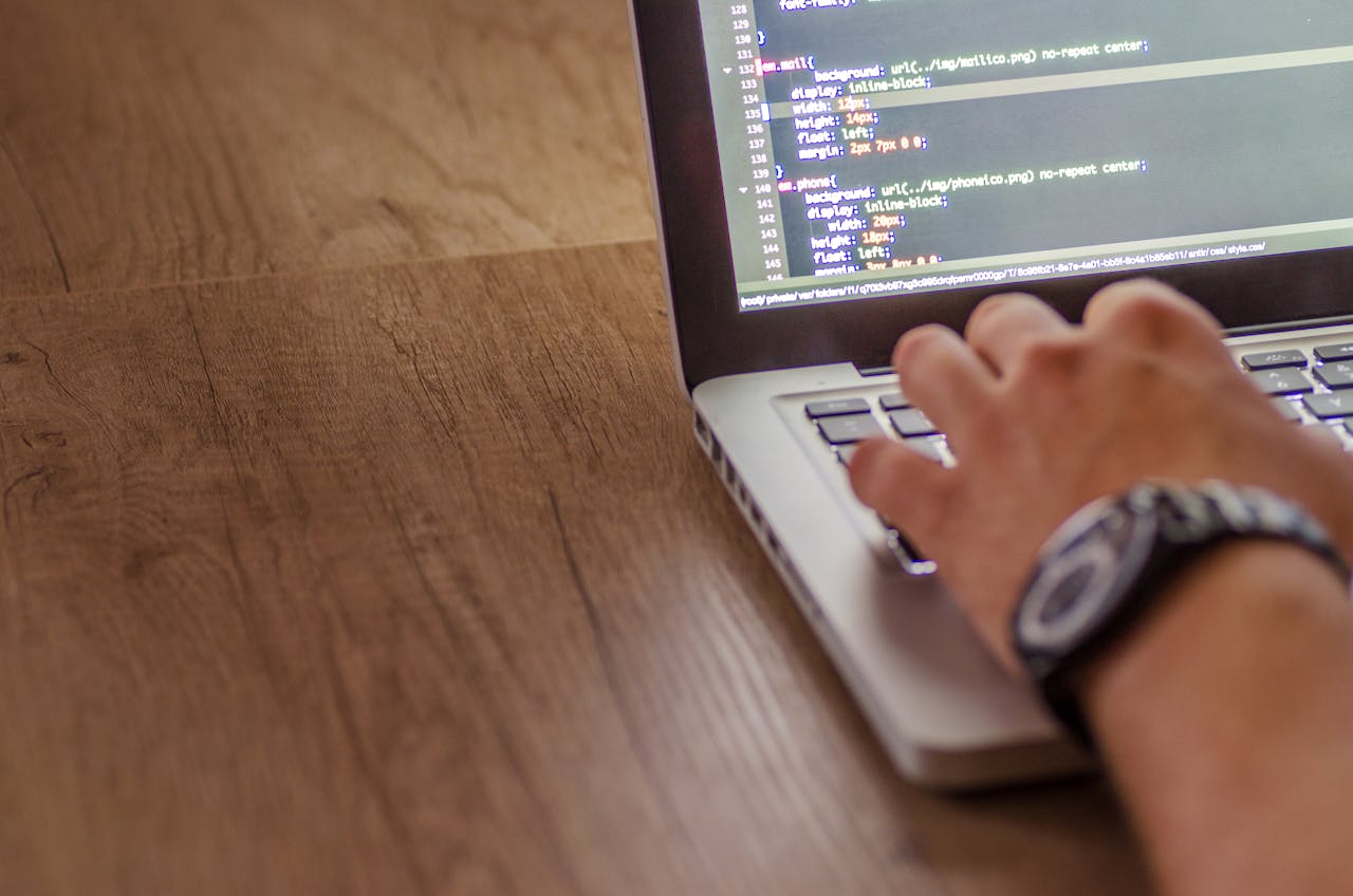 Close-up of a person coding on a laptop, showcasing web development and programming concepts.