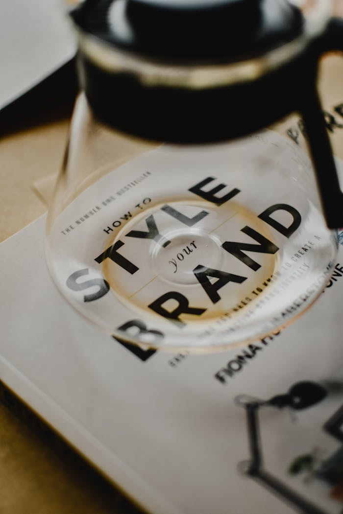 A coffee pot rests atop a book titled 'How to Style Your Brand', capturing the essence of creative branding.